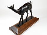 bronze sculpture of a deer on a wooden base on a white background
