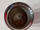 a silver cup sitting on a white table with a shadow of a person