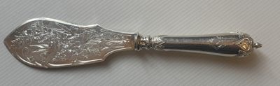 une cuillère en argent avec un manche en argent posée sur une table