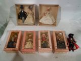 six boxed dolls of different styles and sizes in boxes on a white surface
