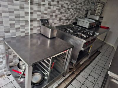 plan de travail en acier inoxydable dans une cuisine commerciale avec des casseroles et des poêles dessus