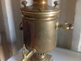 une petite cafetière en laiton posée sur une table blanche