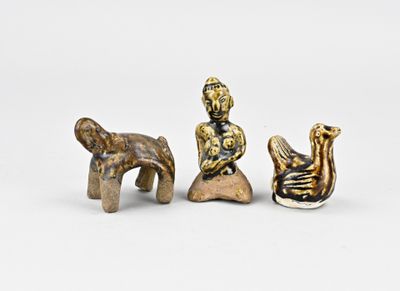 three figurines of a man and a woman sitting on a rock