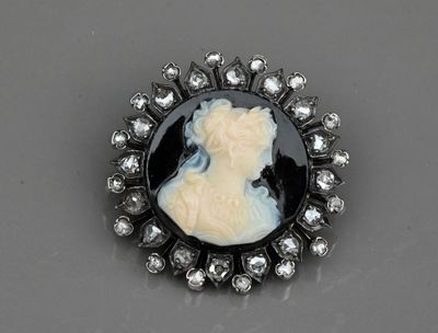 une broche en camée noir et blanc représentant le profil d'une femme, entouré de diamants