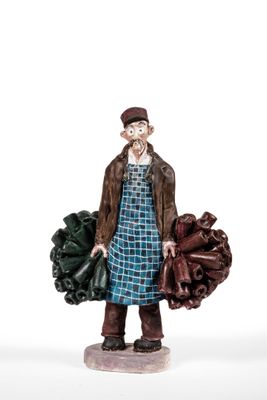 figurine of a man holding a bunch of vegetables on a white surface