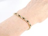 an image of a woman ' s hand wearing a gold bracelet with black stones