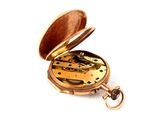 a gold pocket watch that is open on a white surface