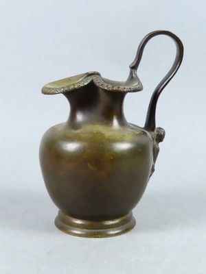 un vase en bronze muni d'une anse, sur fond blanc