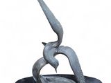 une statue représentant deux oiseaux sur un plateau, sur fond blanc