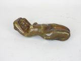 bronze statue of a woman laying on her back on a white surface