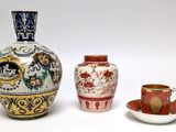 three vases and a cup sitting next to each other