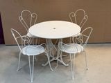 a white table and four chairs in front of a brown wall