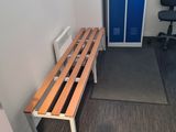 a wooden bench in the corner of a room next to a blue door