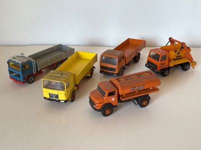 Plusieurs camions miniatures sont alignés sur une surface blanche