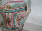 un vase avec une anse qui contient des fleurs