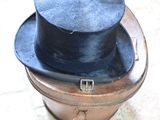 a black top hat sitting on top of an old suitcase