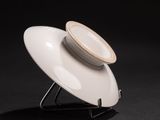 a white plate that is on a stand on a black background