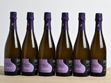 six bouteilles de vin sont alignées sur une table en bois
