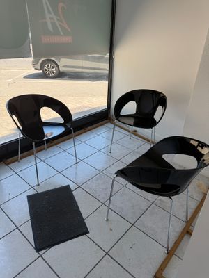 trois chaises noires dans une pièce dotée d'une grande fenêtre