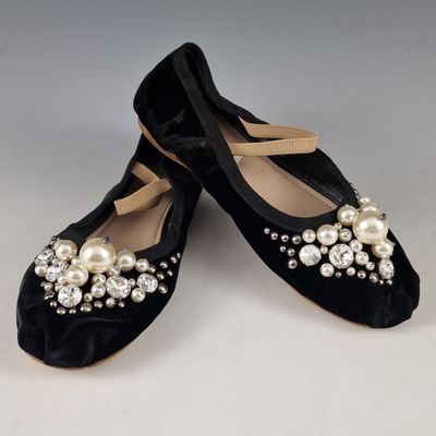 pair of black velvet shoes with pearls and bows on them