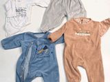 three baby clothes laid out on a white surface