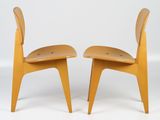 two wooden chairs sitting next to each other on a white surface