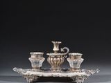un plateau en argent avec trois tasses et une soucoupe posées dessus