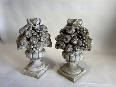 une paire de sculptures représentant des fruits à noyau, posées sur des socles devant un fond blanc