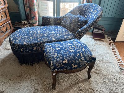 une photo d'un fauteuil et d'un pouf dans un salon