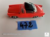 une petite voiture rouge et un tissu bleu posés sur une table