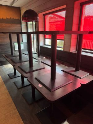 des tables et des bancs dans un restaurant, avec une lumière rouge qui filtre à travers les fenêtres
