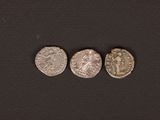 three silver coins are shown on a black surface