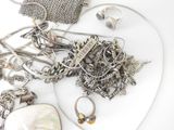 a lot of silver jewelry on a white surface