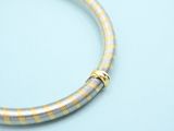 a close up of a yellow and white bracelet on a blue surface