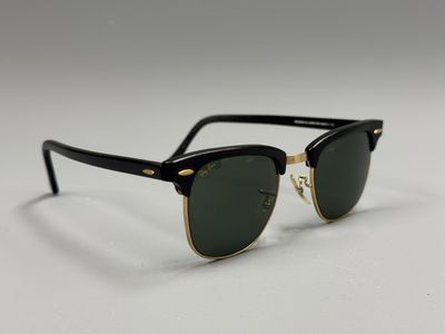 une paire de lunettes de soleil noires avec des montures dorées et des verres verts