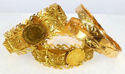 two gold bracelets with a coin on each of them