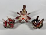 three glass birds sitting on top of a white table next to each other
