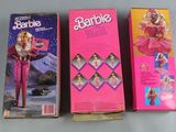 two boxes of barbie dolls sitting on a table next to each other