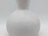 a white vase with a plant in it on a table