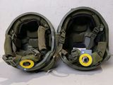 pair of military helmets with yellow buttons on them sitting on a white surface