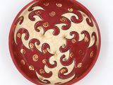 a red bowl with a design on it on a white surface