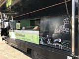 a black food truck with writing on the side of it