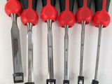 six red and black screwdrivers are lined up on a white surface