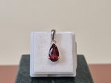 a close up of a pendant with a red stone on a marble block
