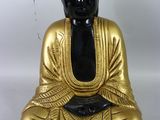 figurine de Bouddha assise sur une surface blanche, avec un fond blanc