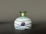 a green vase sitting on a table with a black background