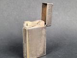 a silver lighter with a metal case sitting on top of a table