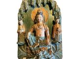 statue of a man sitting on a rock with a group of people in the background