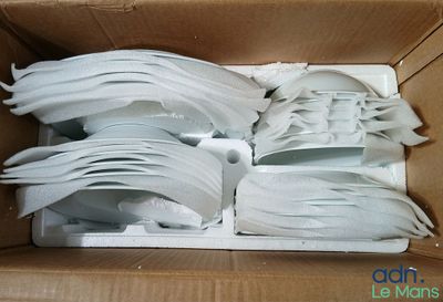 a cardboard box with a bunch of white plastic spoons in it