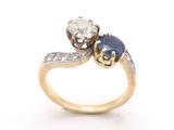 un gros plan d'une bague en or sertie de deux saphirs et d'un diamant